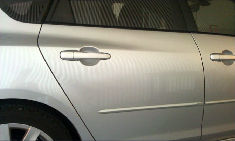 The same silver car door panel after paintless dent repair, smooth with no visible dent